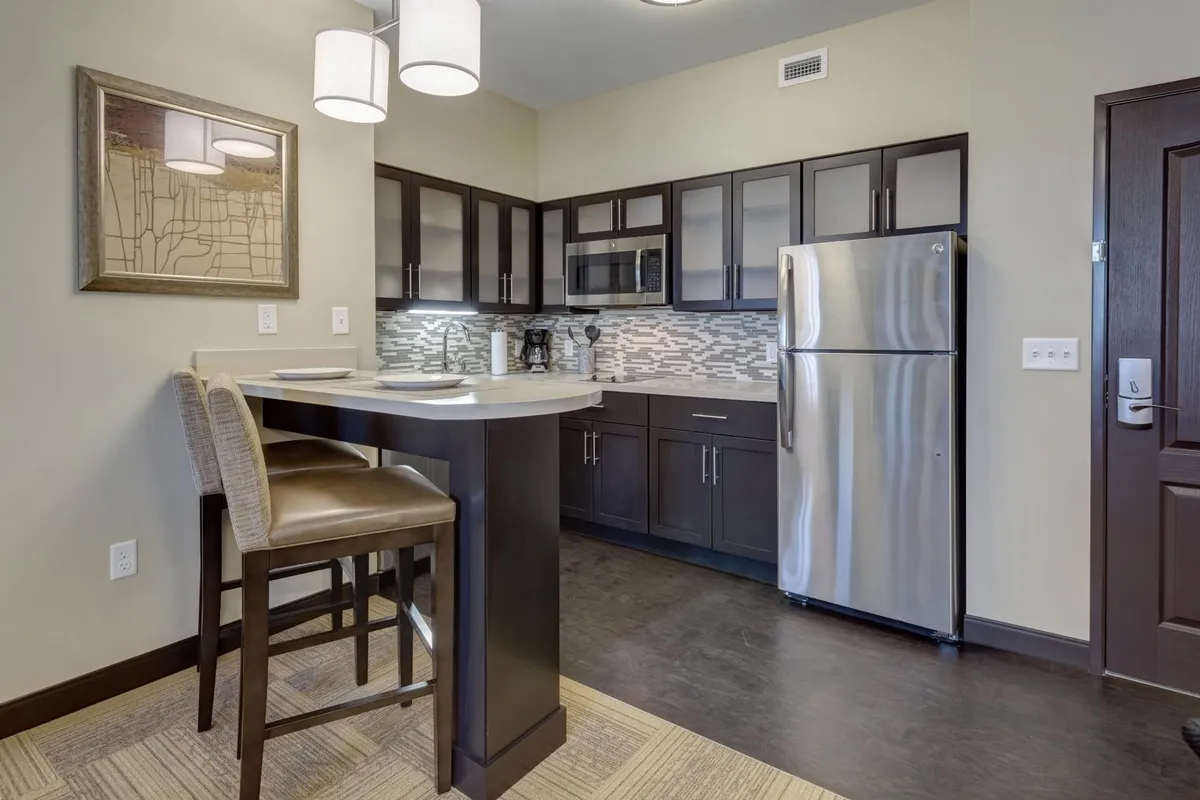 A modern, open-plan kitchen area with a central island, bar stools, and stainless steel appliances. The bright and inviting space is ideal for shared meals, casual gatherings, and entertaining, complementing the suite’s versatile layout.