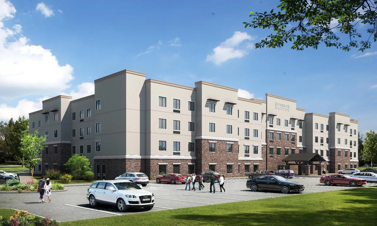 An inviting exterior shot showing the main entrance of the hotel, complete with a welcoming canopy and accessible parking area. The image conveys a sense of arrival and ease for guests checking in with family or groups.